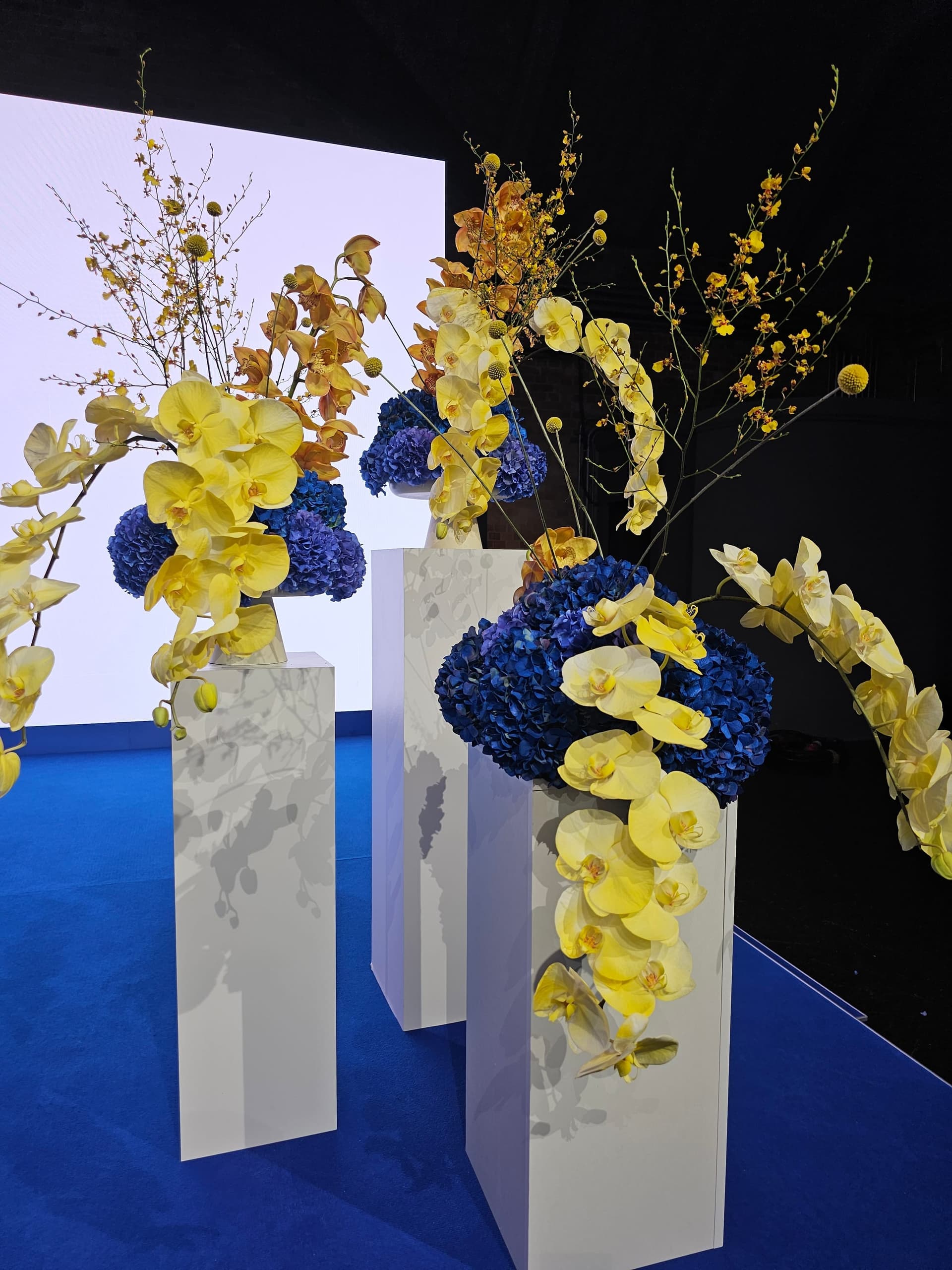Florale Installation mit gelben Orchideen und blauen Hortensien bei einem Business Event