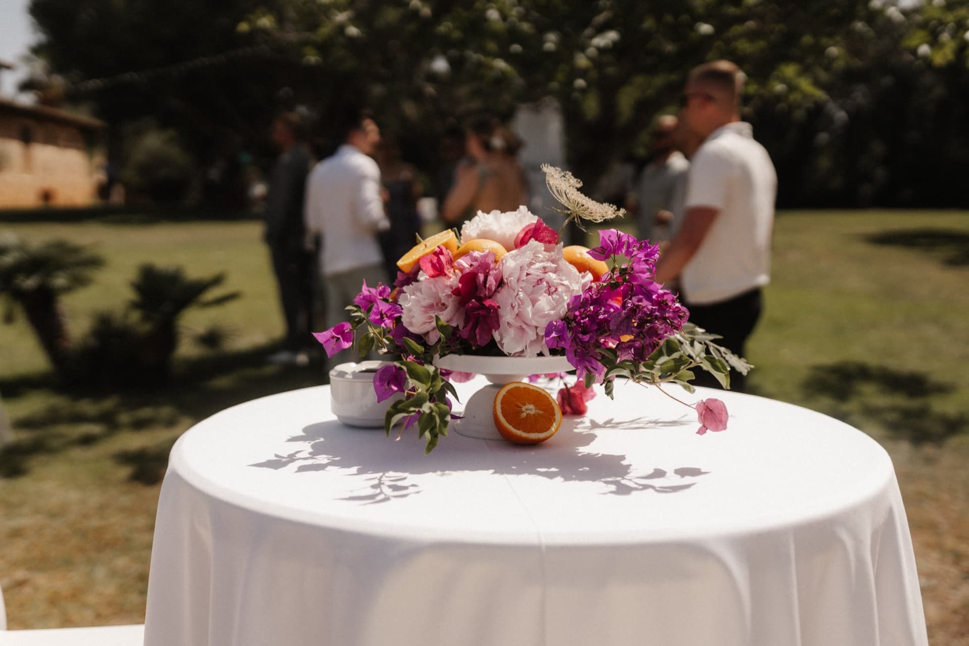 Stehtisch mit Blumenschale aus Pfingstrosen, Bougainvillea und Orangen
