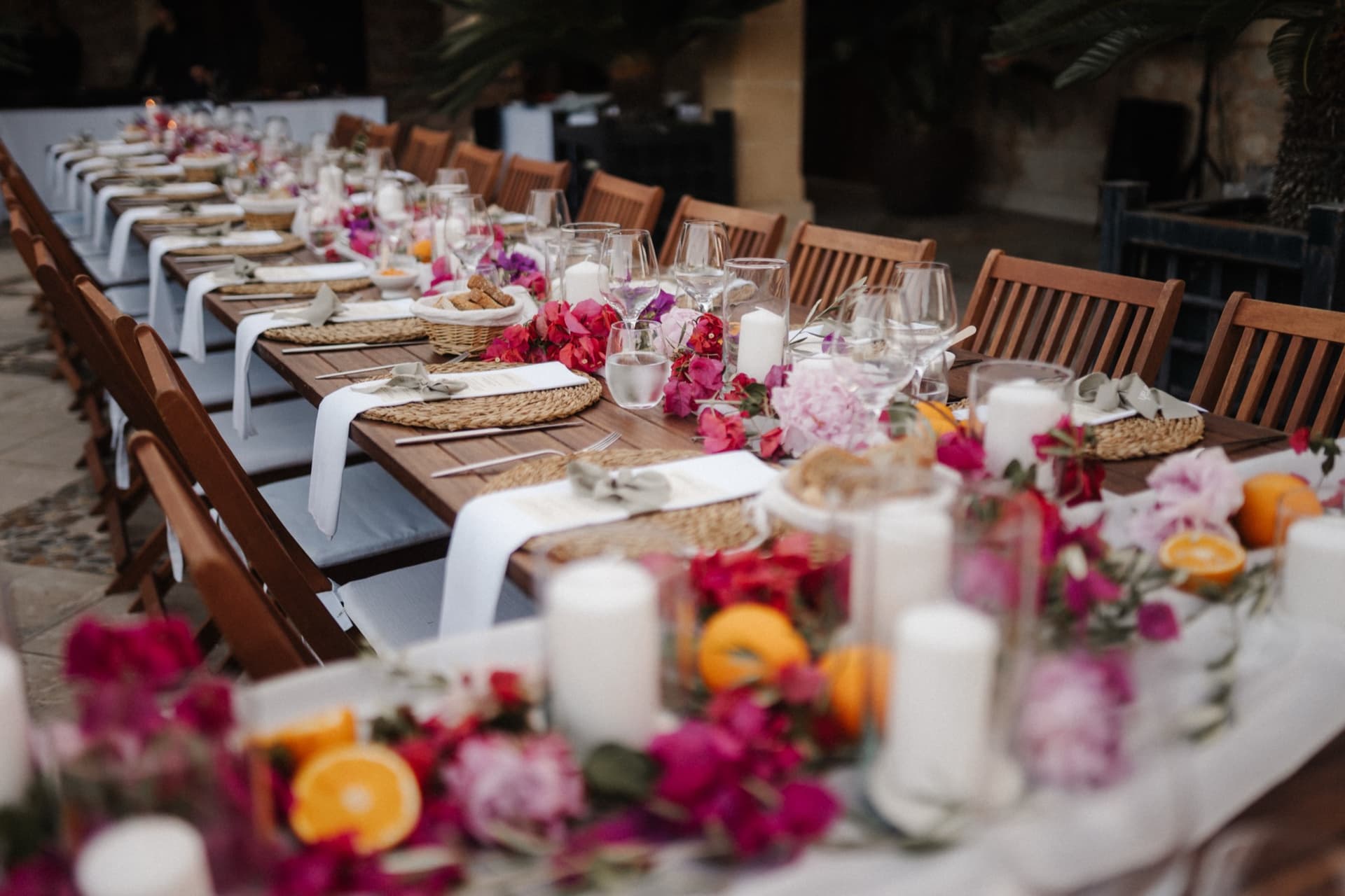 Lange Tafel mit floralem Tischläufer und Kerzen im Innenhof