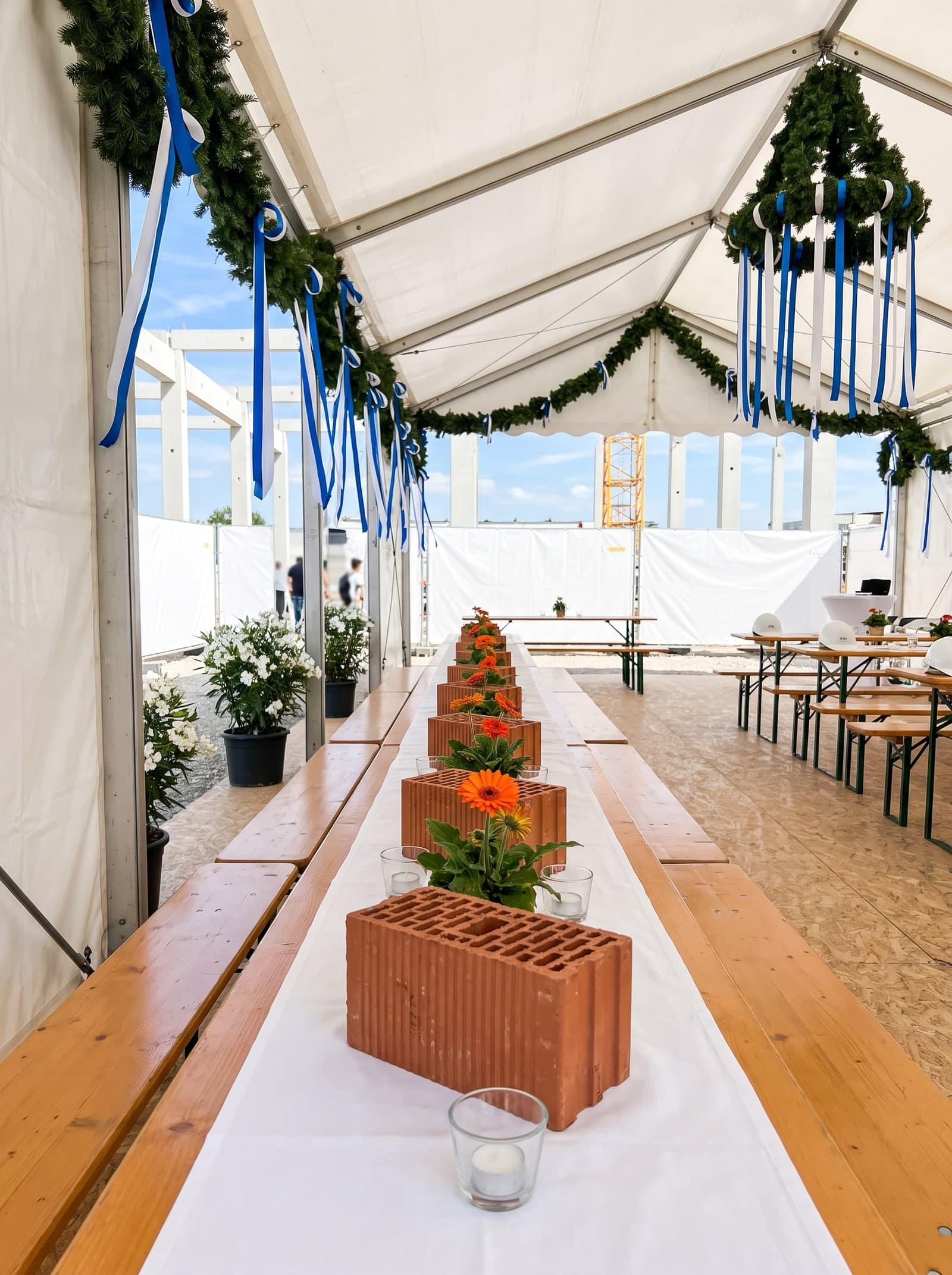 Eingedeckte Bierbanktafel unter dem Zeltdach, Gerbera im Lochziegel